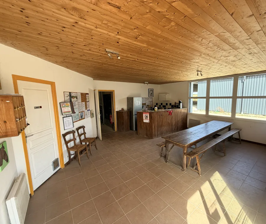 L’accueil : plafond de bois, grande table et bancs, le comptoir au fond
