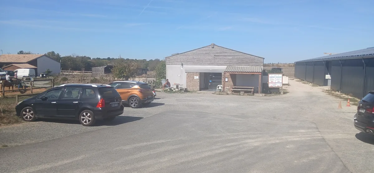 Le club vu du parking : le club house, les écuries et le manège couvert au fond