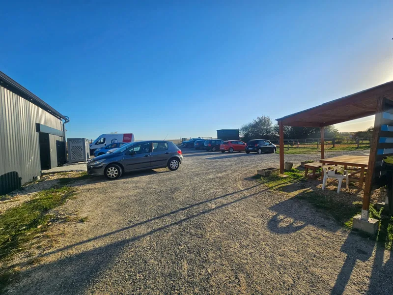 Le parking du club devant le club house, auvent de bois avec table et banc